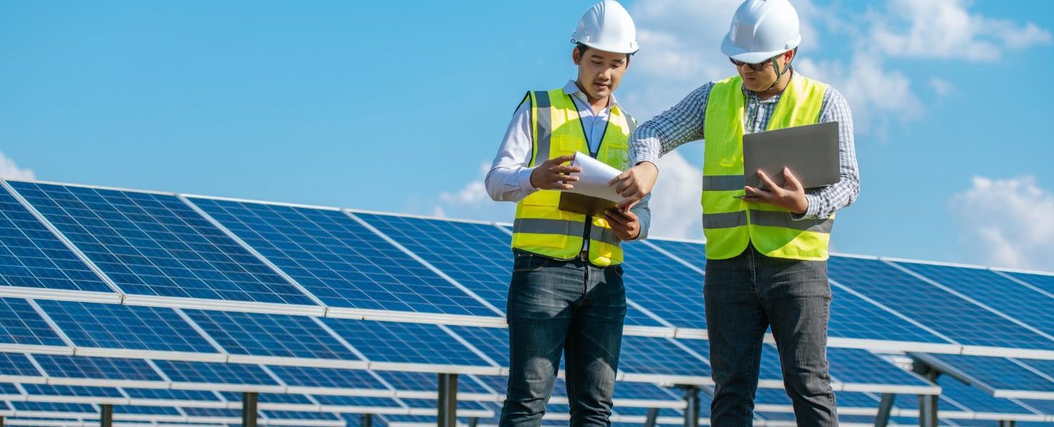 two asian young engineers walking along rows photovoltaic panels solar farm they use laptop computer talking together
